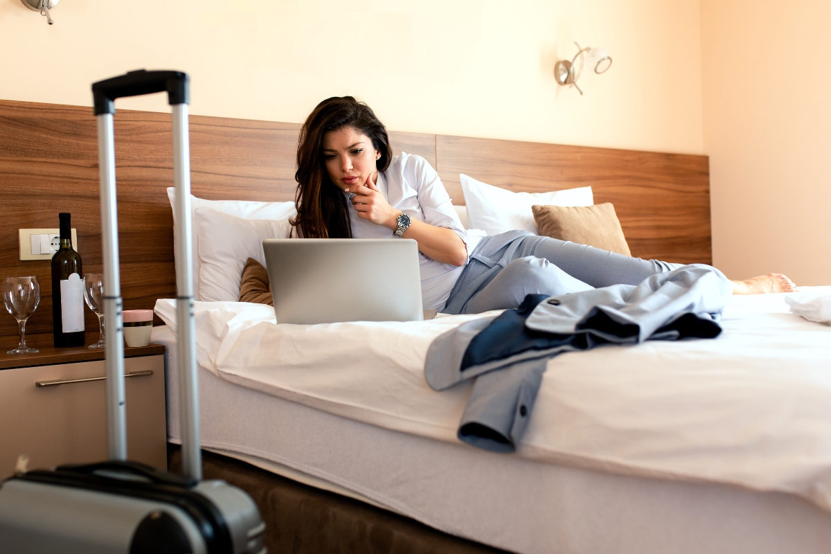 une femme sur son lit d'hotel qui utilise son ordinateur avec vpn