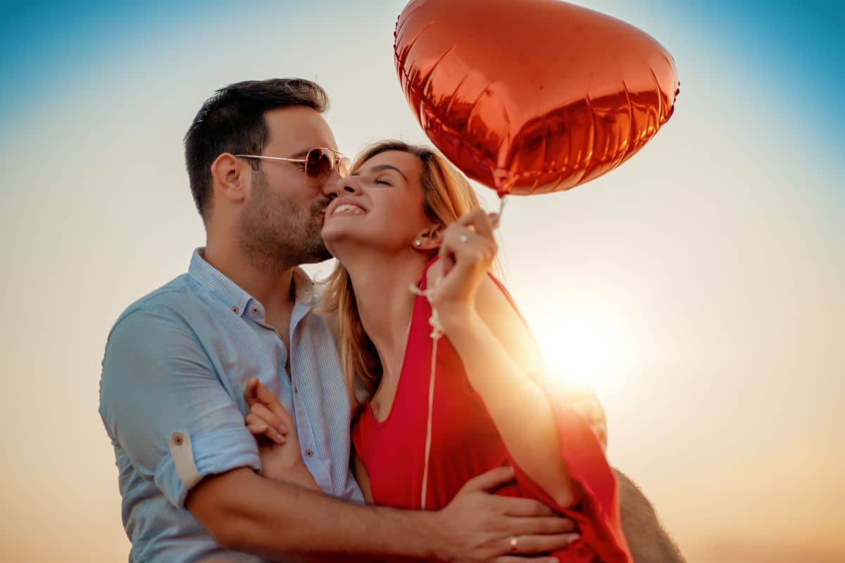 couple amoureux tenant un ballon rouge en forme de coeur