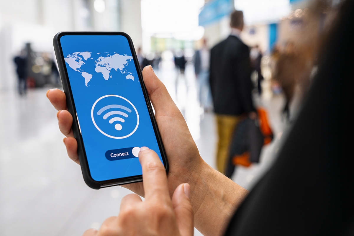 une femme qui utilise son téléphone à l'aéroport pour se connecter à internet avec un VPN gratuit