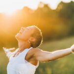 femme qui est apaisée et qui profite de la nature en étendant les bras, affirmations positives, bien-être