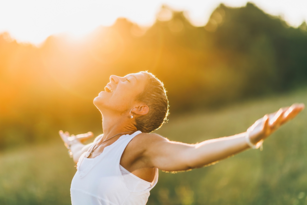 femme qui est apaisée et qui profite de la nature en étendant les bras, affirmations positives, bien-être