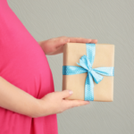 Le ventre d'une femme enceinte recevant un cadeau pour sa grossesse