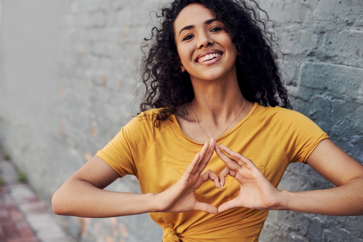 femme apaisée positive qui fait un signe de coeur avec ses mains