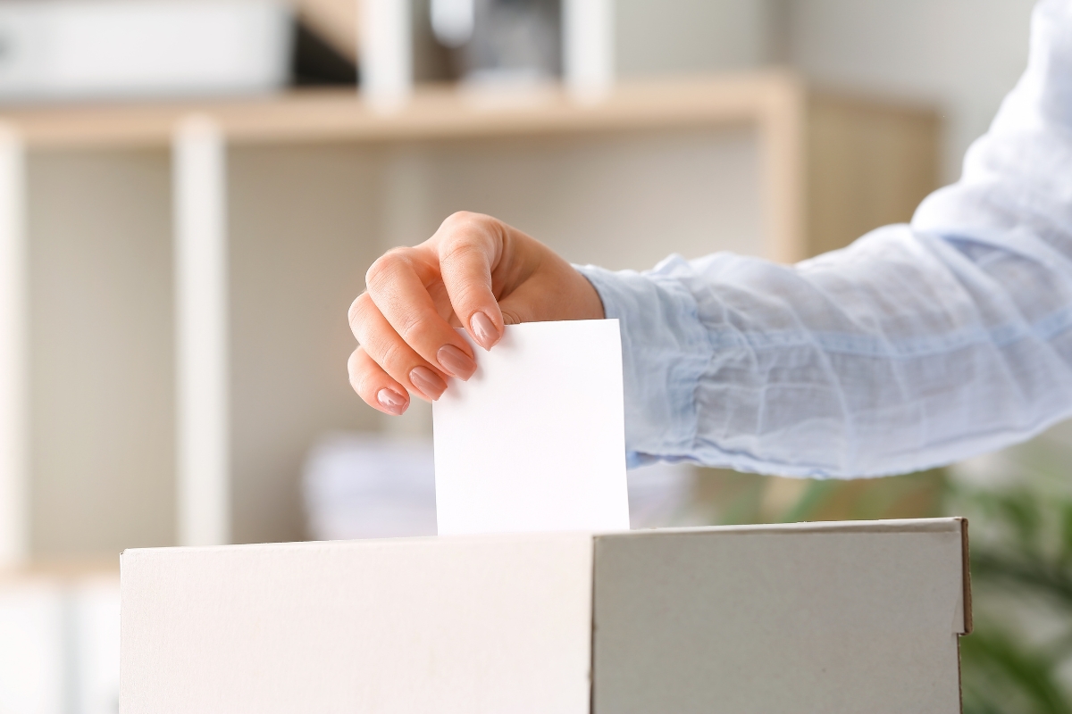 Une main qui vote en inscrivant un bulletin dans une urne