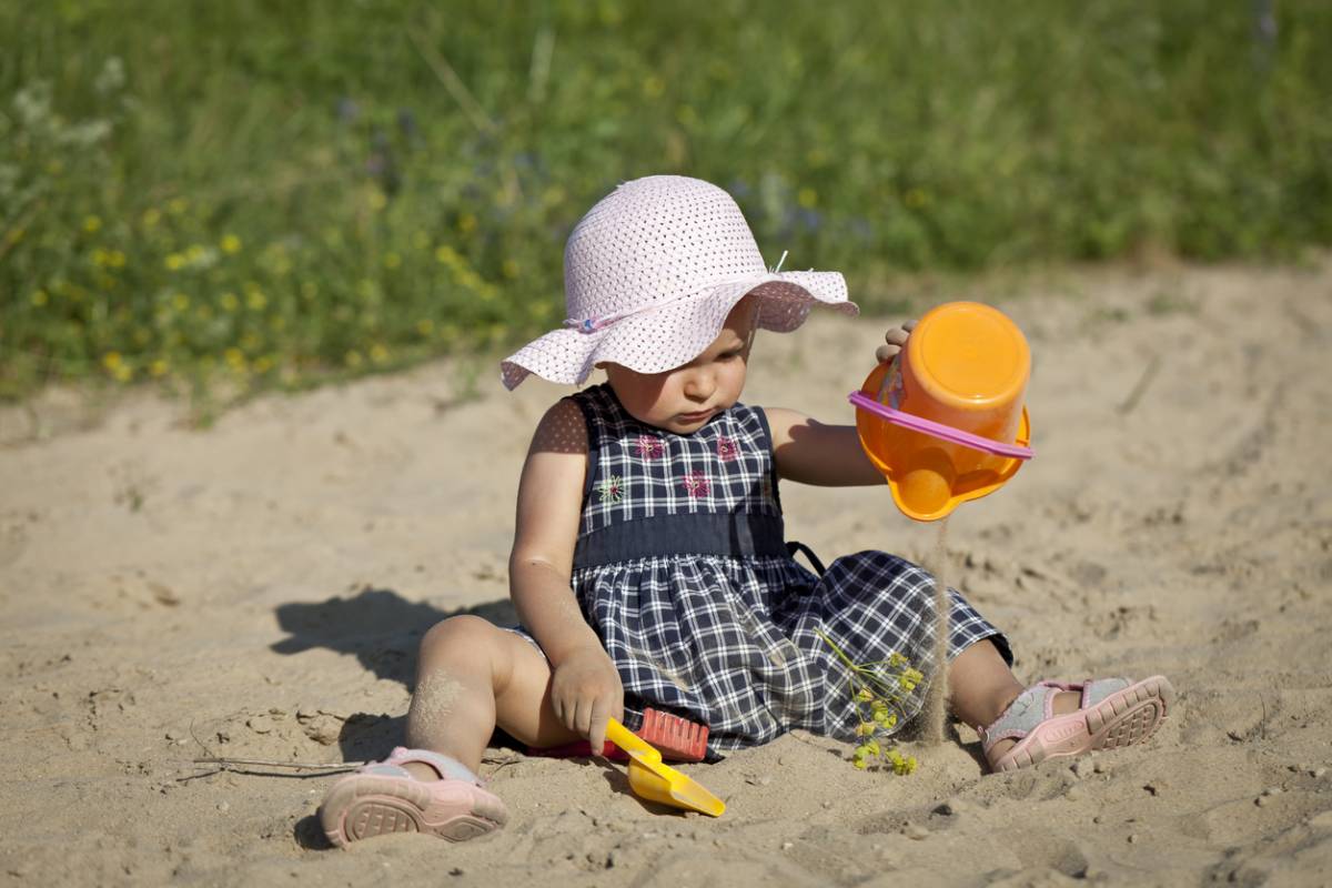 sandales d'eau bébé, une petite fille joue avec du sable sur la plage