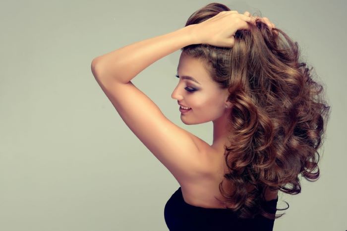 Jeune femme qui a de beaux cheveux et qui utilise de bons soins capillaires