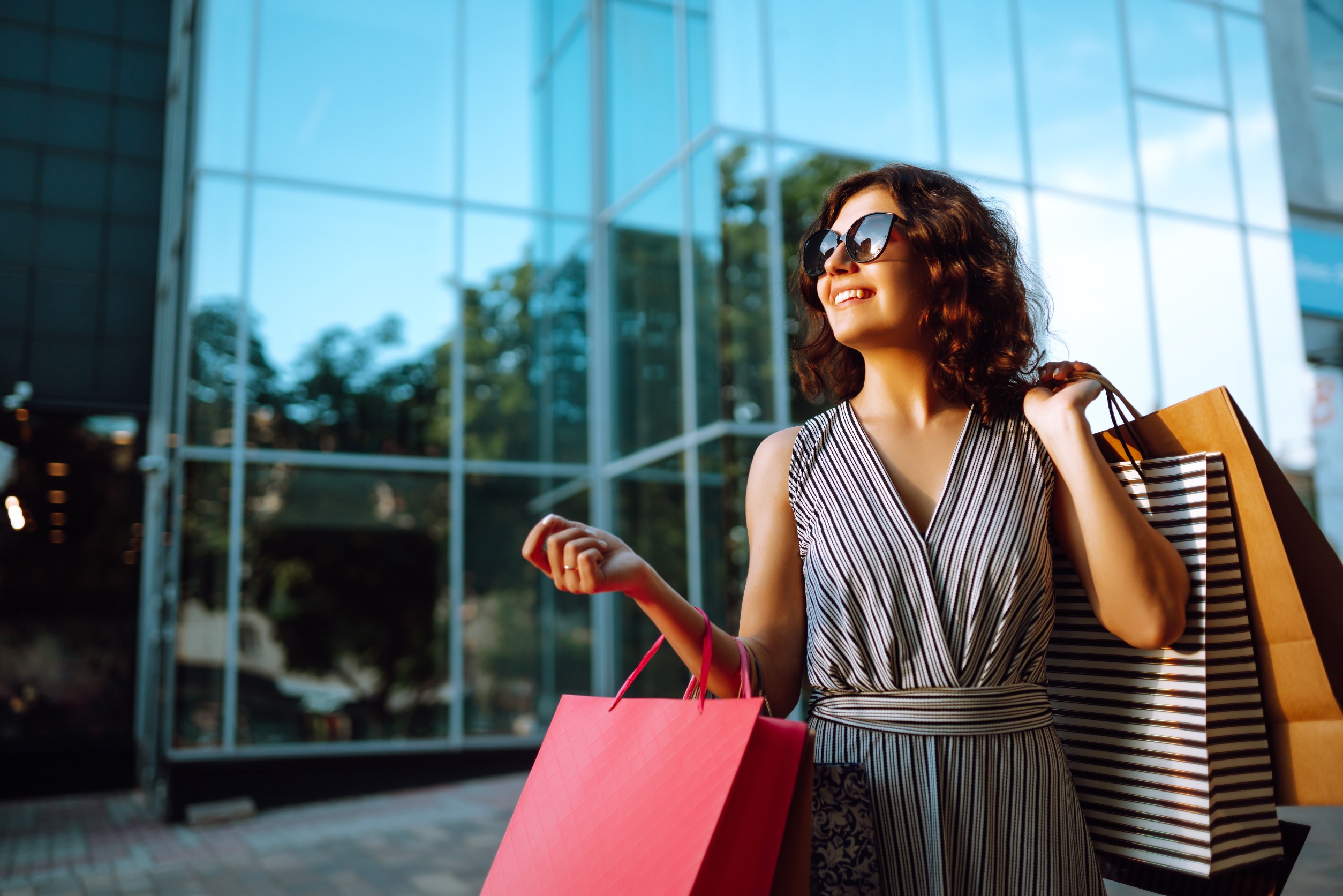 Une femme quarantenaire tres heureuse qui porte plusieurs sacs de shopping