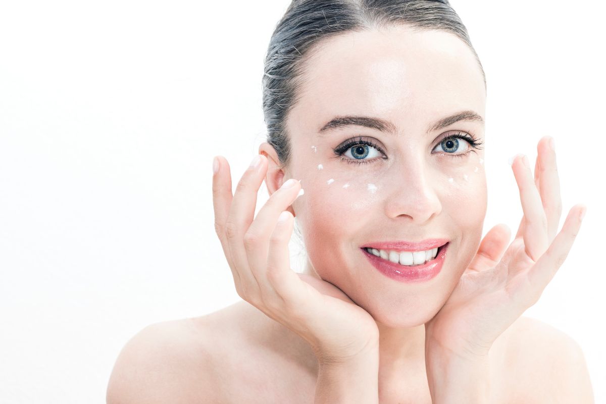 une femme au visage éclatant applique de la crème pour le contour de ses yeux contre la vieillesse de la peau