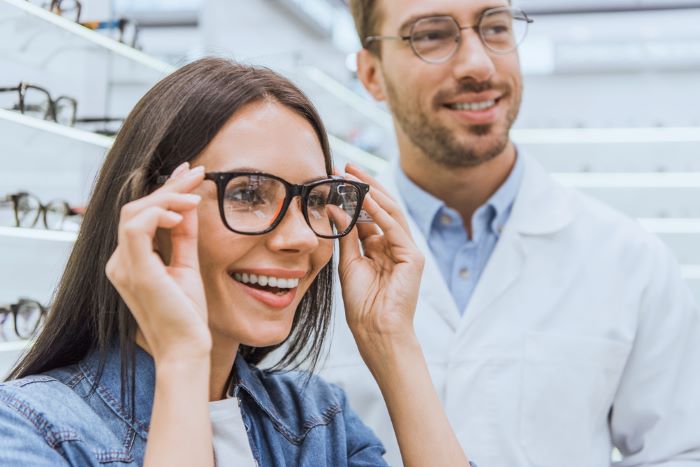 Une femme qui a une bonne mutuelle sante et qui choisit ses lunettes chez un opticien 