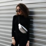 femme fashion sac banane se tient debout en appui sur un mur