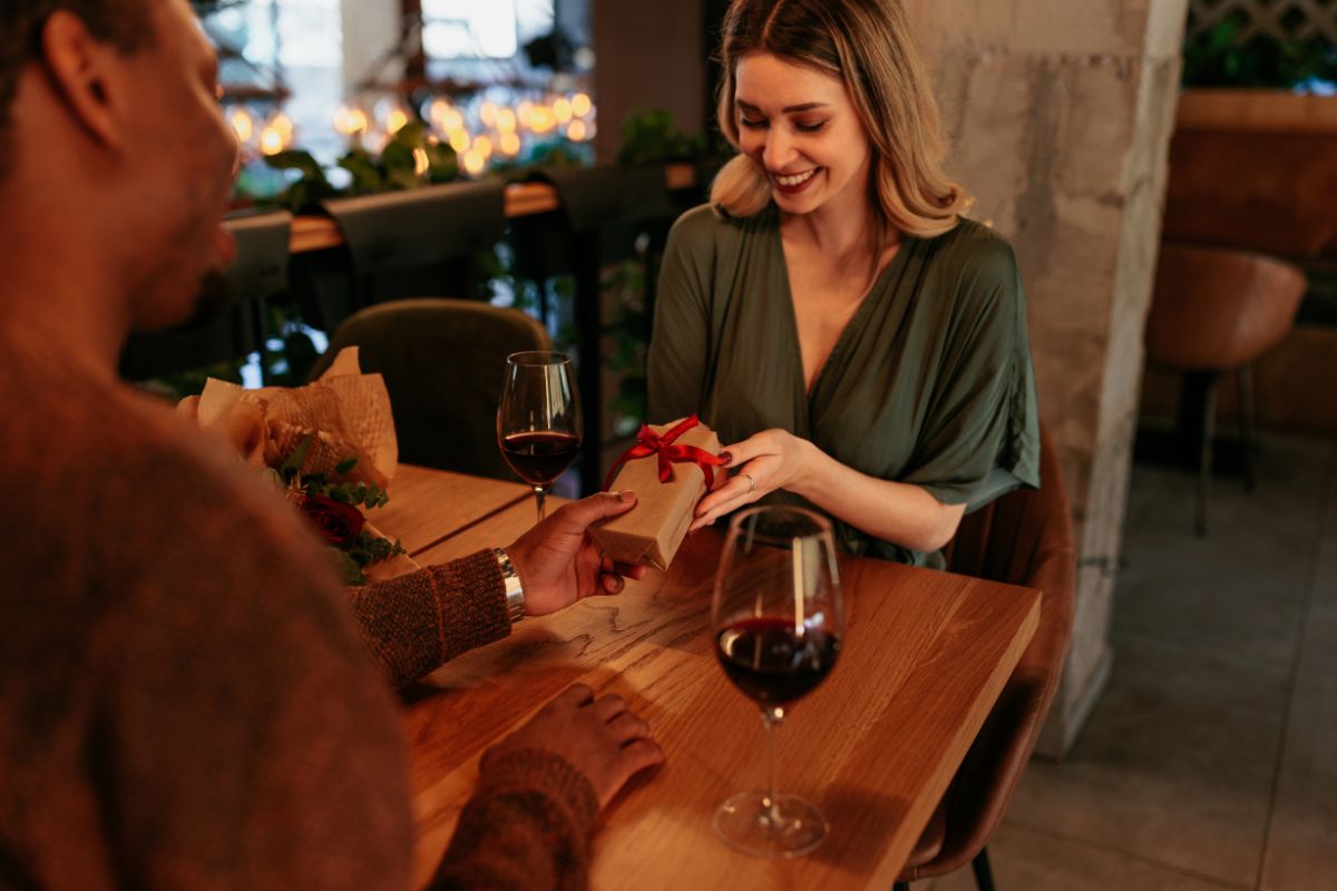 Un homme offre un cadeau à une femme lors d'un diner