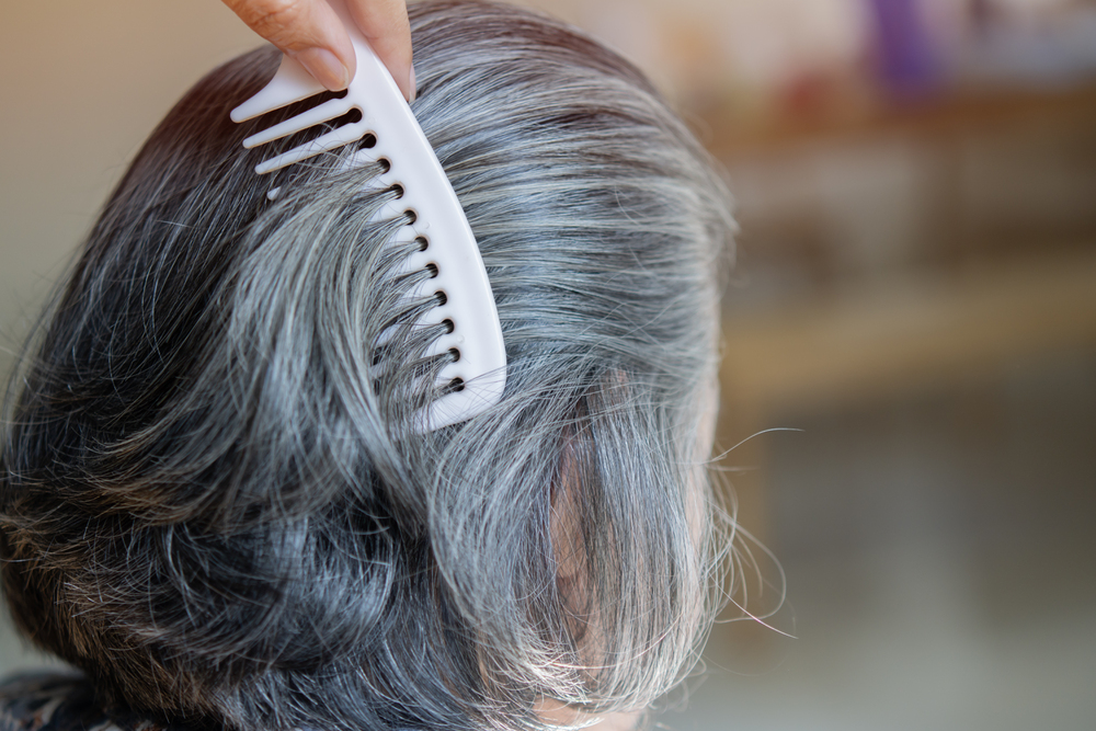 Une main avec peigne chez le coiffeur, coiffe cheveux d'une femme de 60 ans