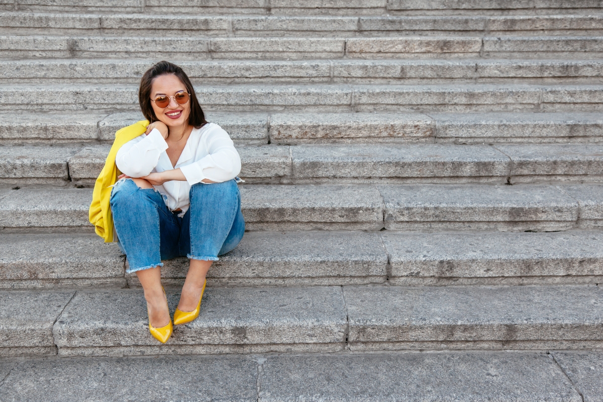 une femme en jean grande taille assise sur les marches d'un escalier