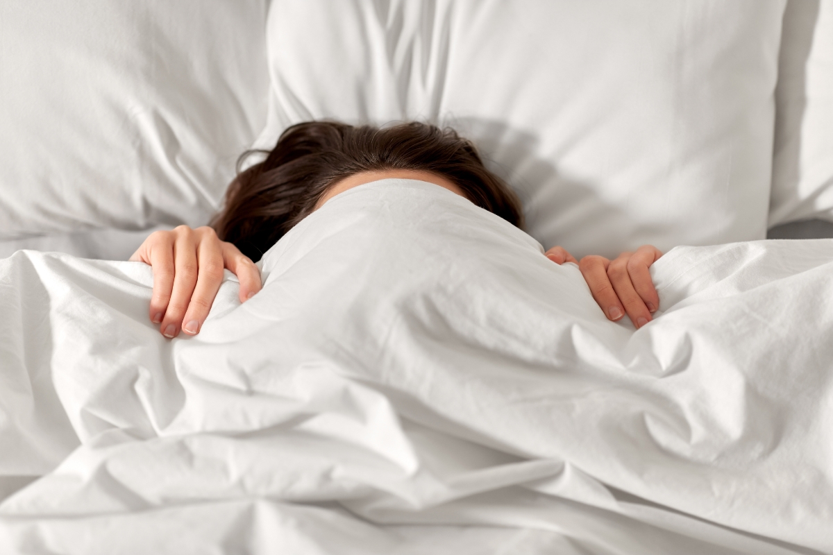 une femme qui cache sa tete sous des draps