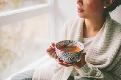 une femme boit une boisson apaisante contre le stress chez elle ambiance cosy cocooning