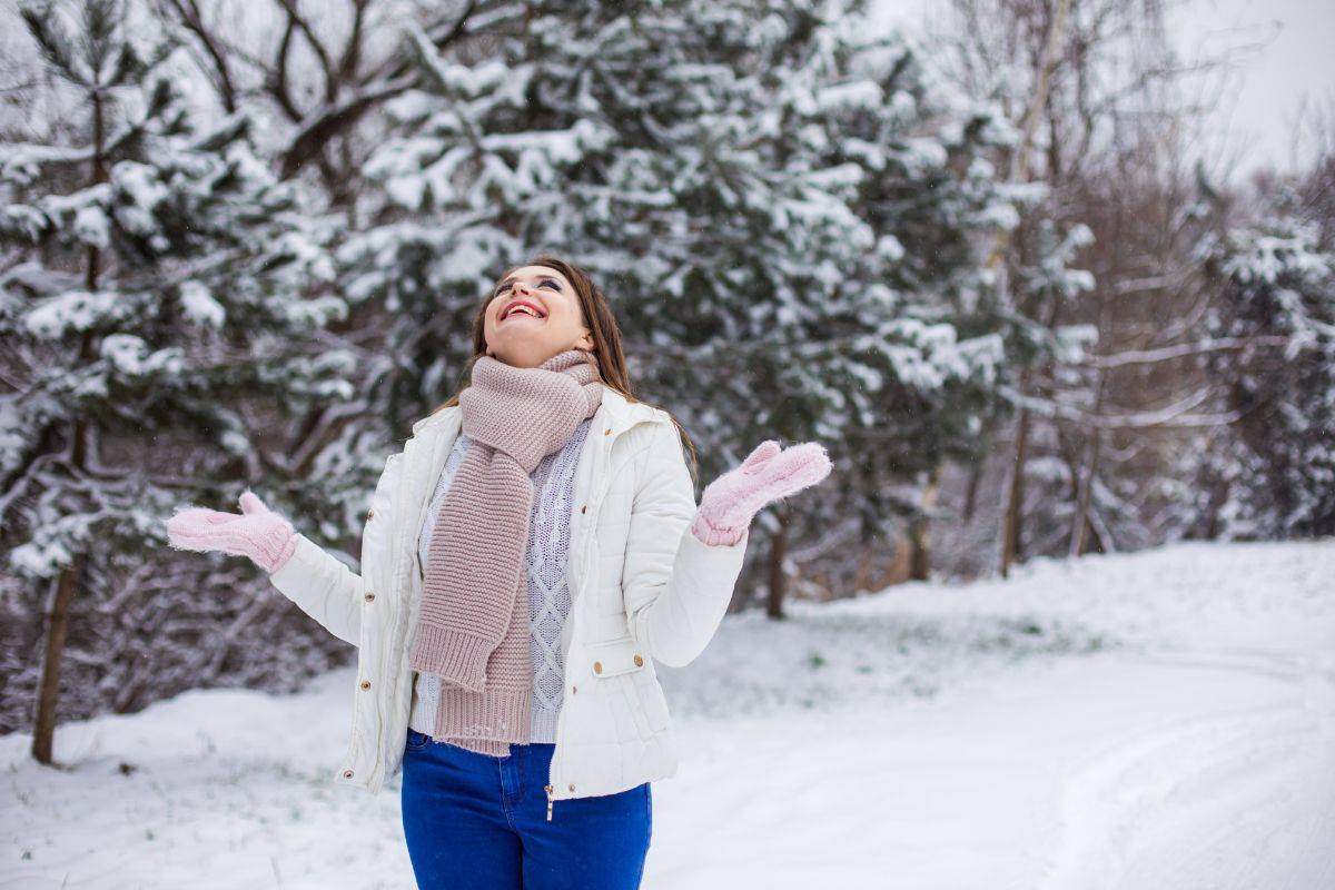 une femme heureuse sous la neige avec des vetements chauffants innovants hiver