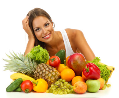 Une femme derrière une pile de fruits et légumes / concept de santé alimentation bien etre