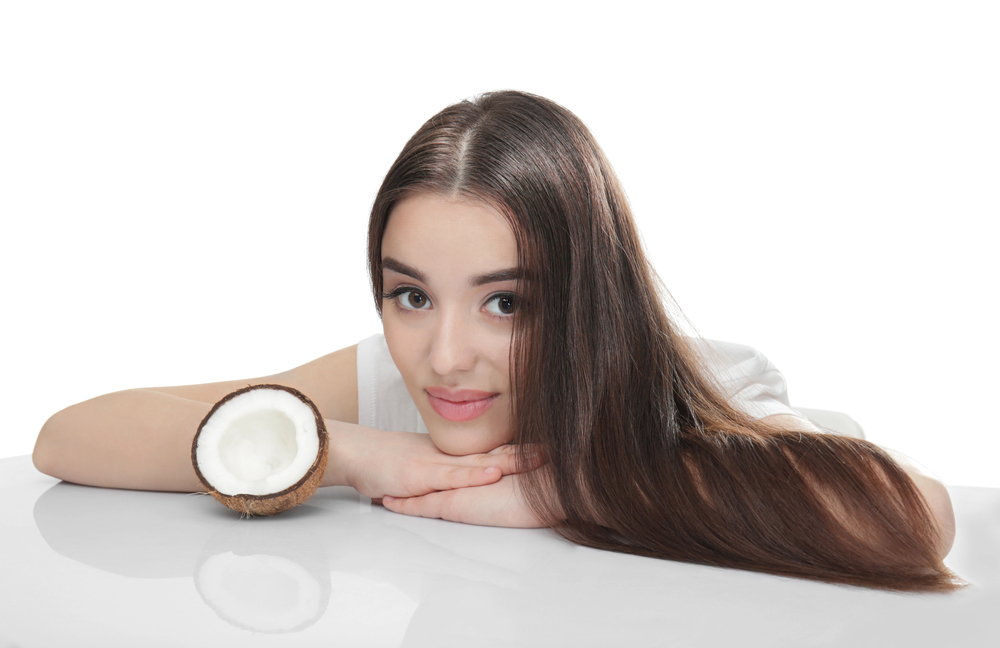 une femme brune aux beaux cheveux utilise de la coco pour ses soins