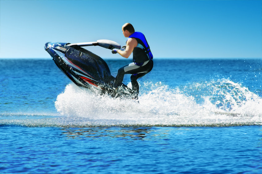 Un personne fait du jet ski sur une belle mer bleue et realise une figure