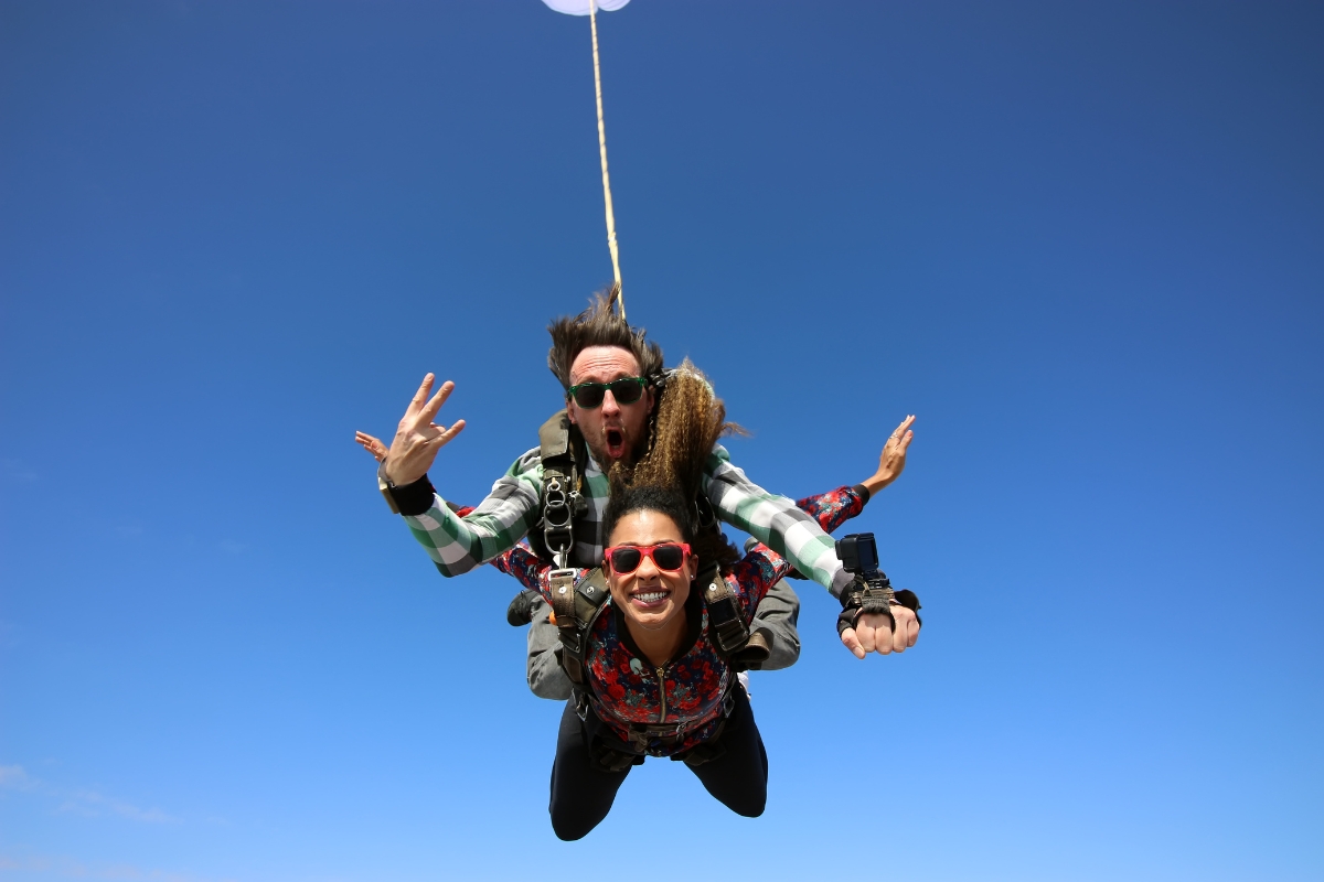 une femme très heureuse qui saute en parachute avec un moniteur pour son enterrement de vie de jeune fille