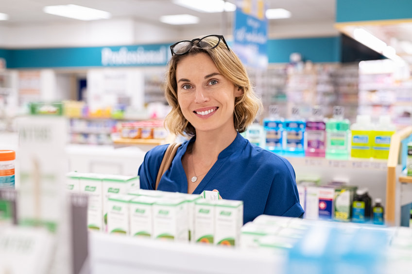 Belle femme blonde a lunettes sur ses cheveux resplendissante qui regarde la camera a la pharmacie et qui choisit des complements alimentaires pour le visage