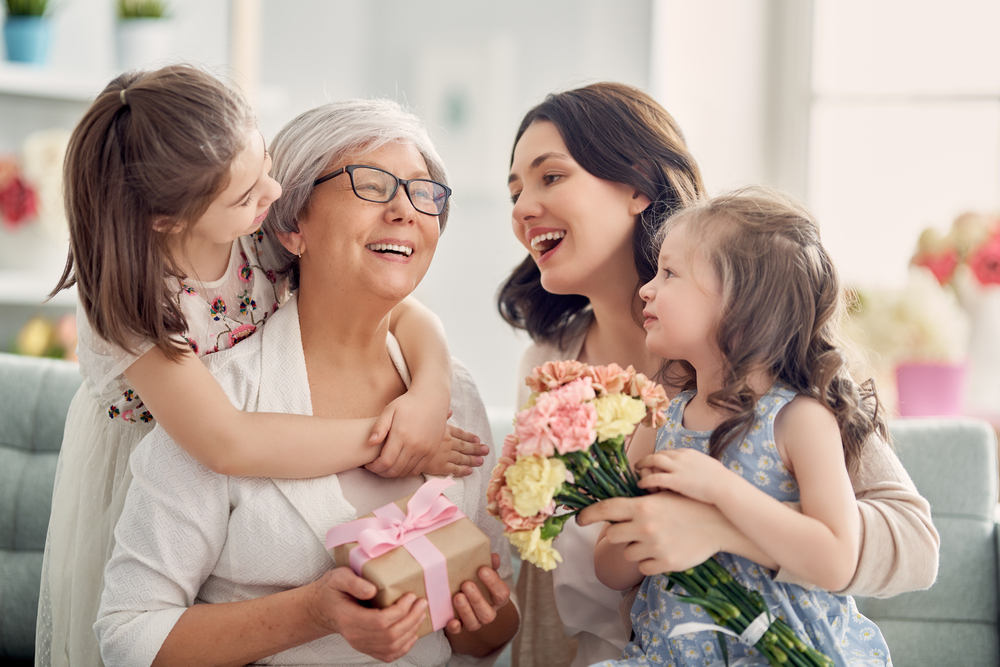 une famille célébrant la fete des grand meres en offrant à mamie cadeaux et fleurs